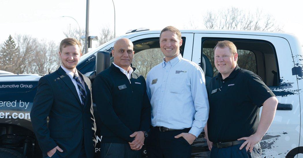 Group of people standing in front of a truck smiling