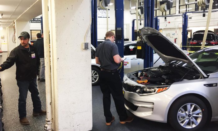 Student looking under the hood of a car