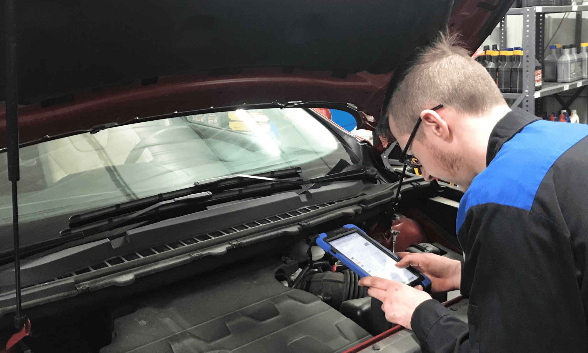 technician using a tablet under the hood of a car