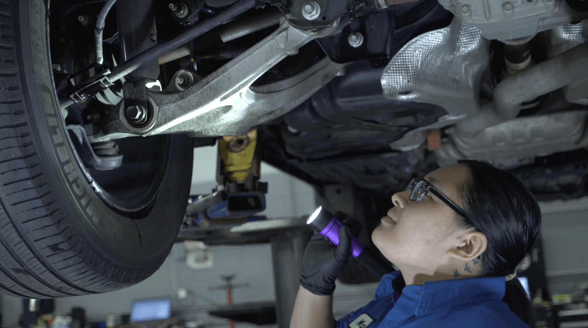 automotive technician looking under a car