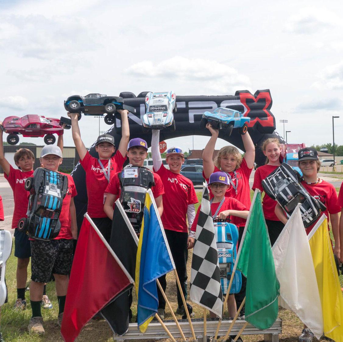 group of campers standing behind racing flags holding up RC cars